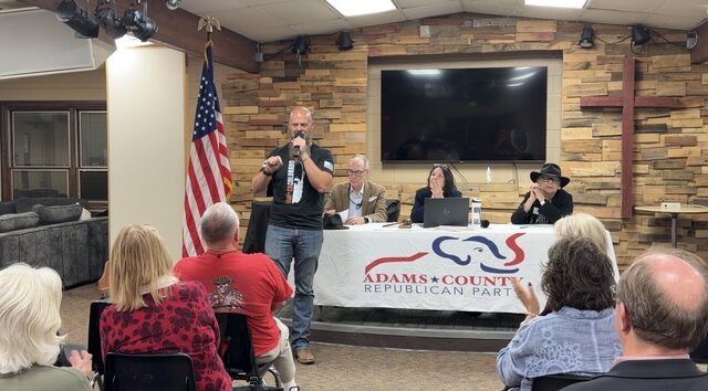 A candidate speaking in front of the Adams County Republican Party banner