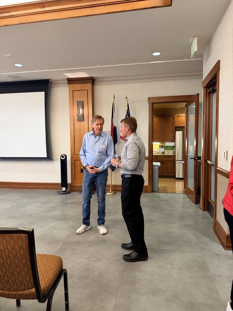 Two guests talking in front of the flags