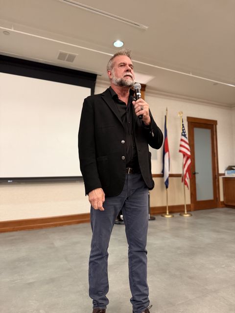 A speaker with a microphone in front of the flags