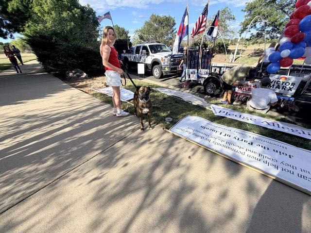 A volunteer and her dog beside the Pledge of Allegiance banner